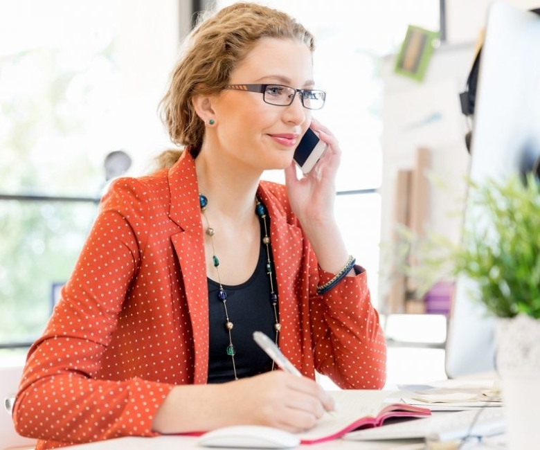 young-woman-holding-mobile-phone-in-office-PE9ARDR-768x640-1.jpg